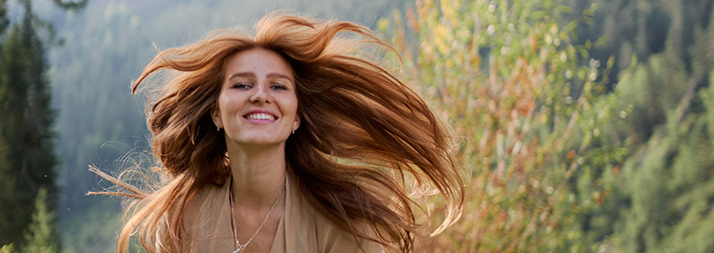 Glückliche Frau, die rennt und deren Haare im Wind fliegen